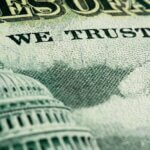 Close-up of a U.S. dollar bill featuring the Capitol building and the words 'WE TRUST', symbolizing U.S. national debt and government fiscal policy.
