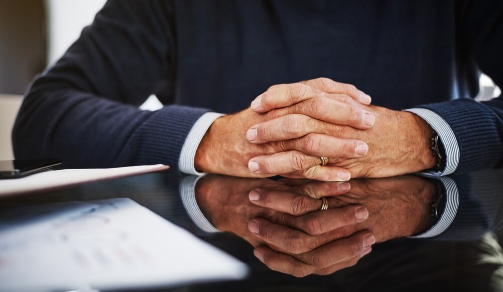 A close-up of a financial advisor's calmly clasped hands resting on a desk, symbolizing a disciplined investment process and the value of objective wealth management advice from Signet Financial Management.